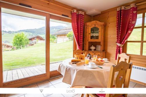 een eetkamer met een tafel en een groot raam bij Sur Le Feug Appt 14 in Combloux