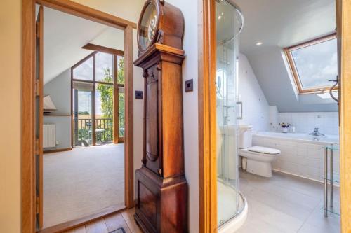 a bathroom with a glass shower and a clock at The Granary, Dunstall Green 