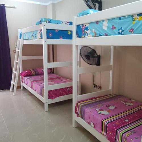 two white bunk beds in a room with a bed at Sweet Home Hostel - ممنوع للبنات المصرين in Hurghada