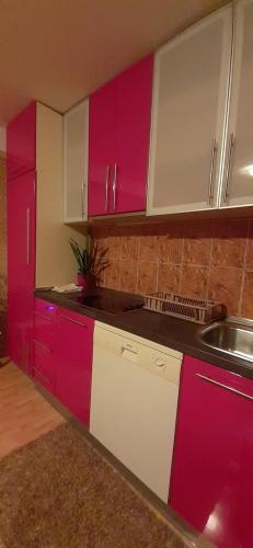 a kitchen with red and white cabinets and a sink at Apartmani Becic in Sutomore