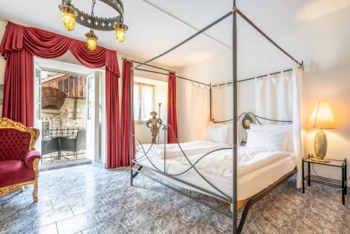 ルツェルンにあるアルトシュタット ホテル マジック ルツェルンのベッドルーム(四柱式ベッド1台、椅子付)