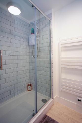 a shower with a glass door in a bathroom at Luxury retreat 32c pool jacuzzi games bar oasis in Deal