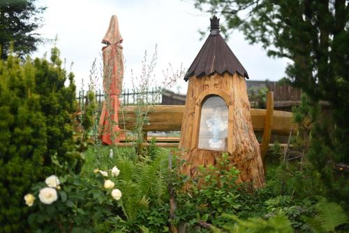 a garden with a tree stump house with a window at U SKUPNIÓW Gliczarów Górny in Biały Dunajec
