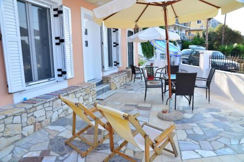 a patio with chairs and an umbrella on a house at Astacos Studios in Paleokastritsa