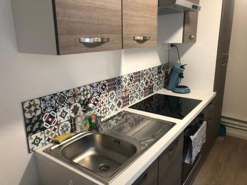 - une cuisine avec un évier et du carrelage sur le mur dans l'établissement Résidence chêne percé Appartement au RDC 51 m2, à Dieppe