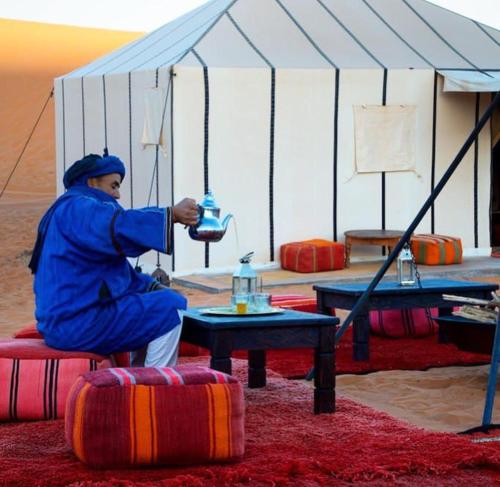 un hombre en una tienda con una mesa en una habitación en Mari Desert Camp, en Merzouga