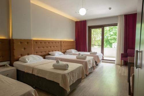 ein Hotelzimmer mit 3 Betten und einem Fenster in der Unterkunft Edirne Adres Karaağaç in Edirne