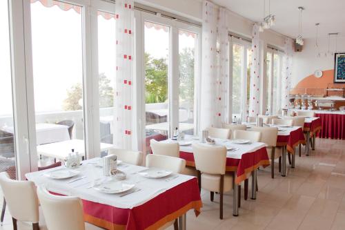 un restaurant avec des tables blanches, des chaises et des fenêtres dans l'établissement Hotel Vali Dramalj, à Crikvenica