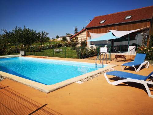 une piscine avec deux chaises et un parasol dans l'établissement Gite de la roseraie, à Louchy-Montfand