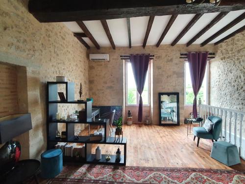 a living room with a wooden floor and purple curtains at Le Mas Réolais in Saint-Sève