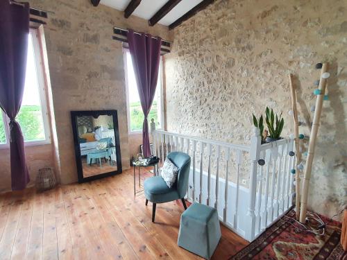 a living room with a chair and a mirror at Le Mas Réolais in Saint-Sève