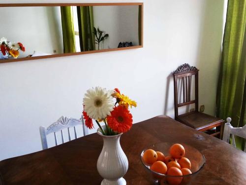 a vase with flowers and oranges on a table at Lemon Tree Apartments in Faro