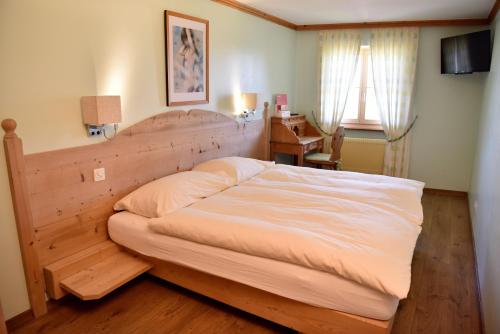 a bedroom with a large bed with a wooden headboard at Hôtel de Ville in Gruyères