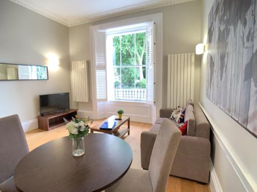 un soggiorno con tavolo e divano di Queen Victoria Apartments a Londra