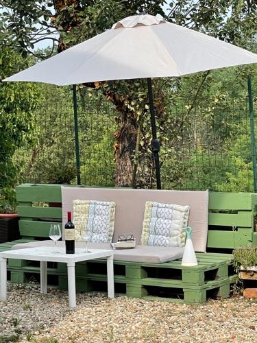 a green bench with an umbrella and a table at Tenuta Nissole in Rocchetta Tanaro