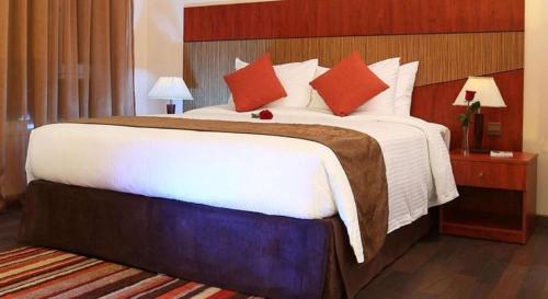 a hotel room with a large bed with red pillows at Best Western Plus Salmiya in Kuwait