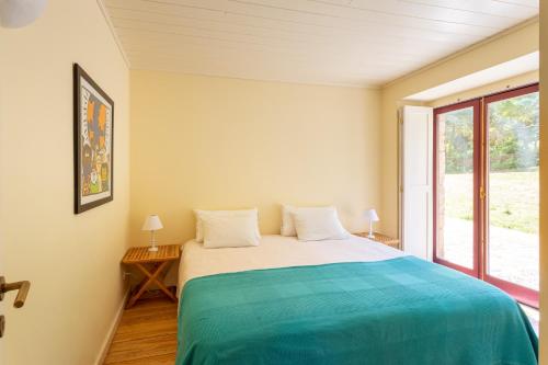 a bedroom with a large bed and a window at Quinta de Fermil - Casas in Vouzela