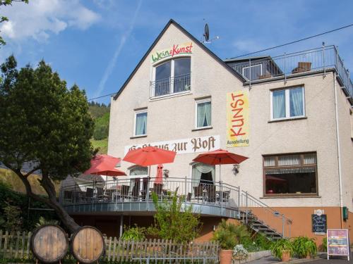 a building with tables and umbrellas in front of it at Hotel zur Post - Burg an der Mosel in Burg an der Mosel