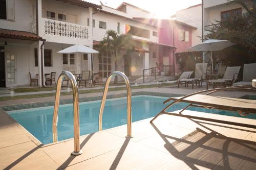 a swimming pool with two chairs next to a building at Vila Hibisco Pousada e Apart in Vassouras