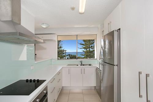 a white kitchen with a sink and a refrigerator at Solnamara Beachfront Apartments in Gold Coast