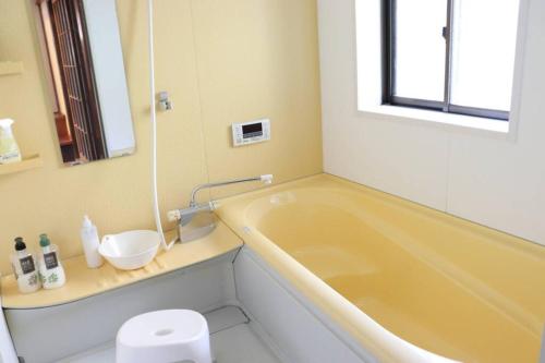baño con bañera amarilla y lavamanos en リテックス浦安, en Tokio