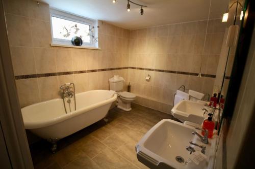 y baño con bañera, aseo y lavamanos. en Springwell Inn, en Pendine