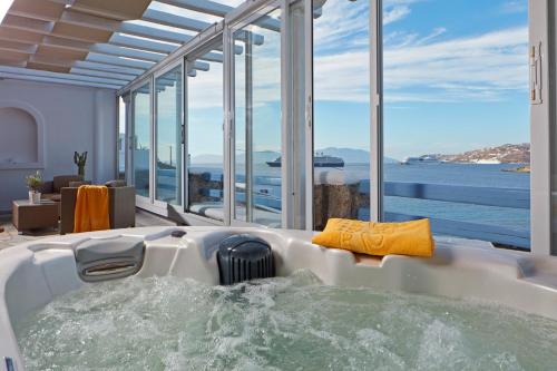 a bath tub in a room with a view of the ocean at Grand Beach Hotel in Mýkonos City