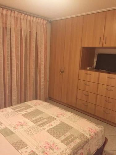 a bedroom with a bed and a cabinet and a television at Siga Siga Apartment in Megara