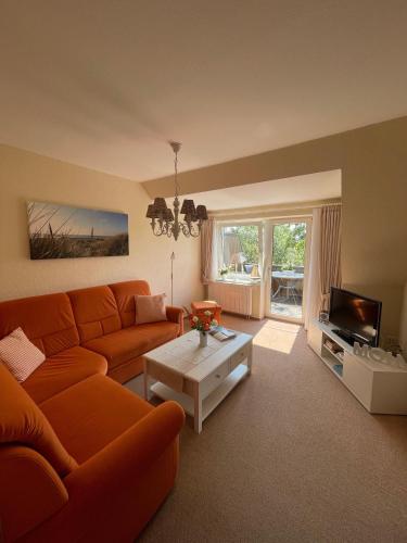 - un salon avec un canapé orange et une table dans l'établissement Haus-Seeschwalbe-Wohnung-2, à Nieblum