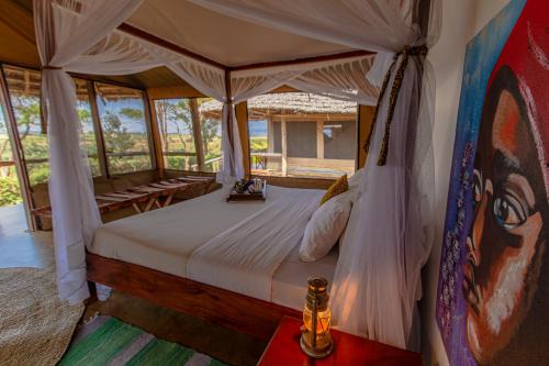 - une chambre avec un lit à baldaquin dans l'établissement Karatu Tented Lodge, à Karatu