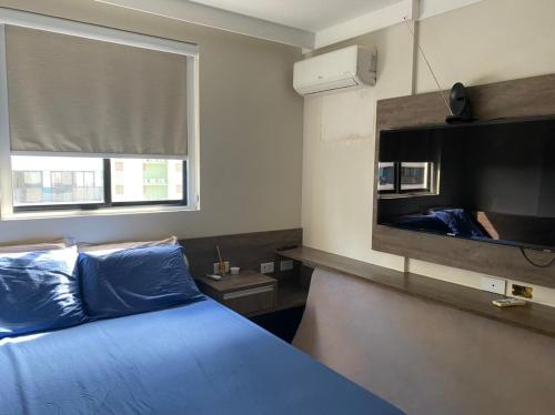 a bedroom with a blue bed and a flat screen tv at Maceió Pajuçara Ed. Neo 1 in Maceió