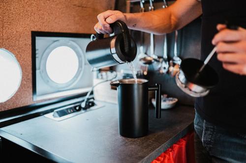 a person pouring coffee into a pot on a stove at Antonov im Garten – Flugzeug-Ferienwohnung in Altendorf
