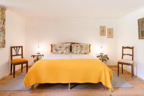 a bedroom with a bed with a yellow blanket and two chairs at Ferienhaus Nöstlbach in Pittenhart