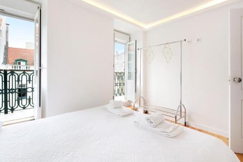 a white bedroom with a bed and a window at Cosy Room in Alcantara - Lisboa in Lisbon