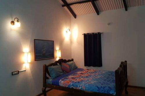 a bedroom with a bed and two lights on the wall at Le Rêve Holiday Home in Coonoor