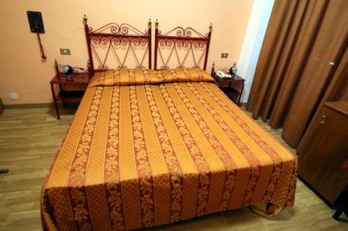 a bed with an orange bedspread in a bedroom at Hotel Italia in Turin