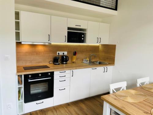 a kitchen with white cabinets and a wooden counter top at Residence Kotel in Rokytnice nad Jizerou