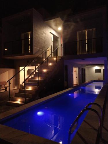 a swimming pool at night with a staircase in the background at Balli Suítes in Ilha Comprida