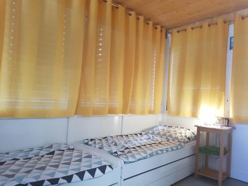 Cama pequeña en habitación con cortinas amarillas en Kleblach 90, 9753 Lind im Drautal, en Kleblach