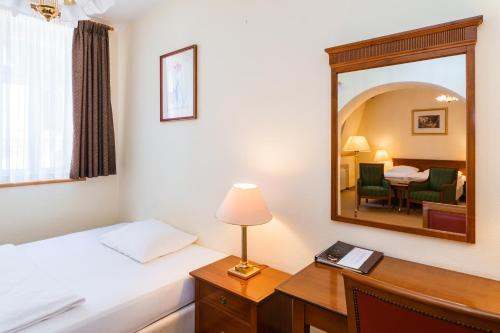 a hotel room with a bed and a mirror at Spa Hotel Anglický Dvůr in Karlovy Vary