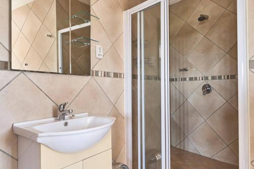 a bathroom with a sink and a shower at Villa Sardinia Guest House in Midrand