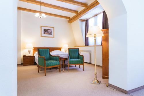 a room with a table and chairs and a lamp at Spa Hotel Anglický Dvůr in Karlovy Vary