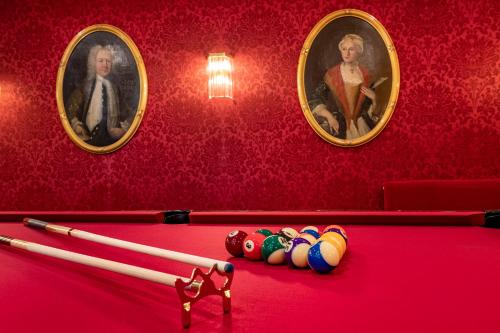 a billiard table with two portraits in a red room at Theaterhotel & Suites Wien in Vienna