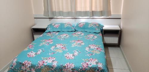 a bed with a blue comforter and pillows on it at Apto 2 quartos no centro de Bombinhas, 130 metros praia in Bombinhas