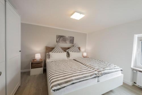 a white bedroom with a large bed and a window at Ferienhaus an den Maaren in Schalkenmehren