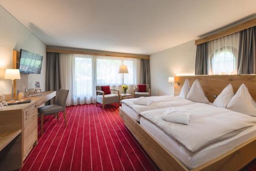 a hotel room with a large bed and a desk at Sunstar Hotel Klosters in Klosters