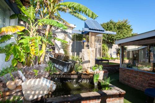 a garden with a pond in front of a house at Strand Guesthouse in Strand