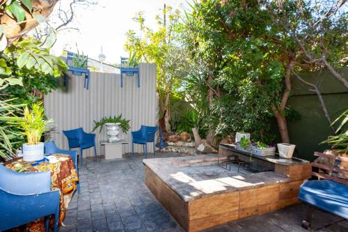 a patio with a table and blue chairs and a fence at Strand Guesthouse in Strand
