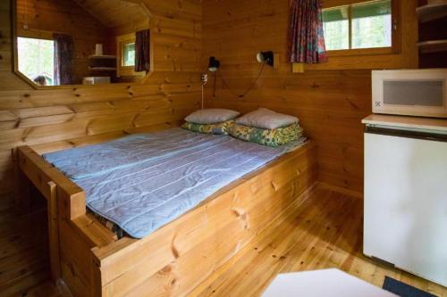a bed in a wooden room in a cabin at Kuus-Hukkala in Harkala