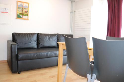 a living room with a black leather couch and a table at Royal Swiss Apartments in Ringgenberg